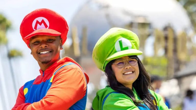 A couple in matching Mario and Luigi outfits smile at the camera,